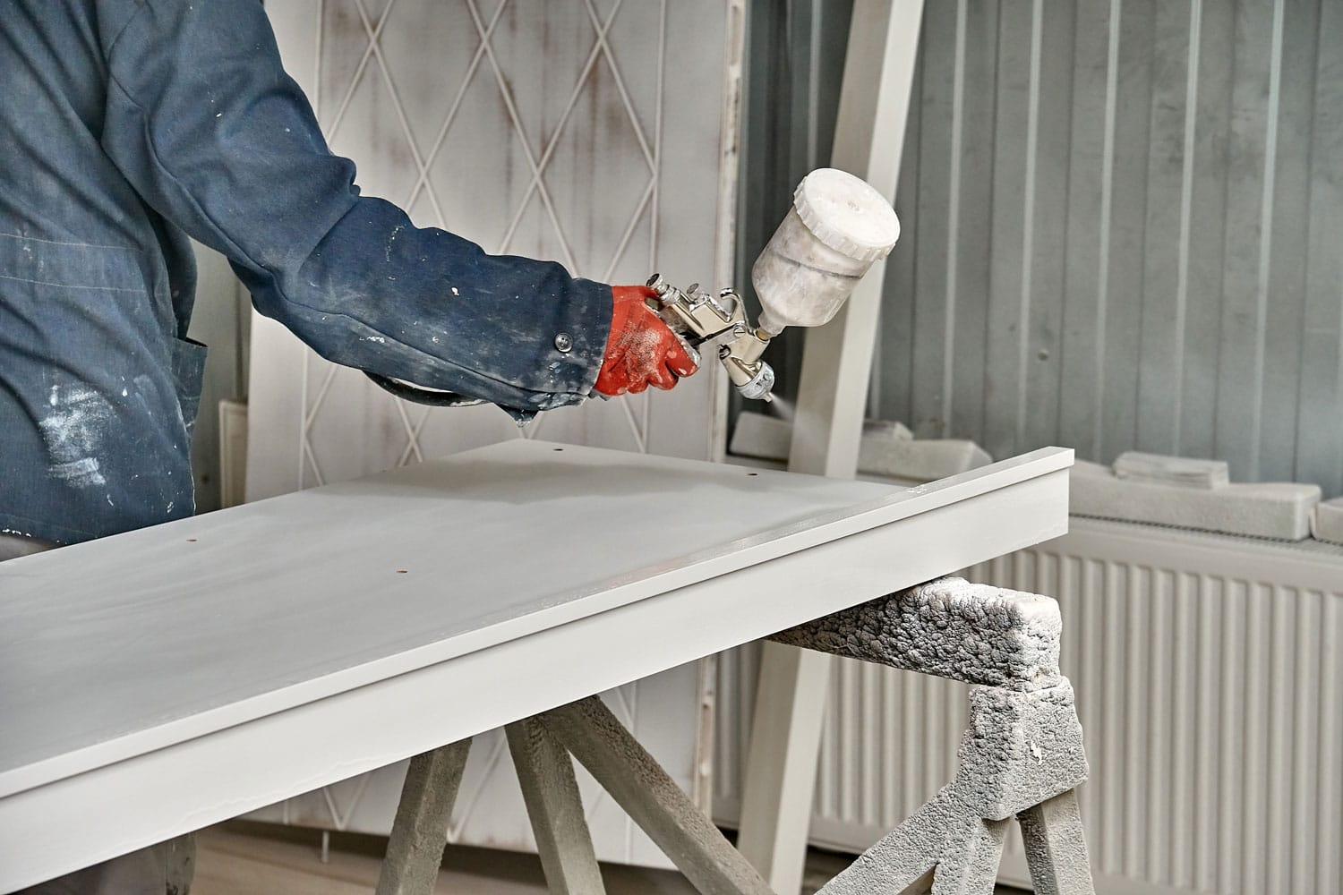 Worker spraying cabinet with gray paint