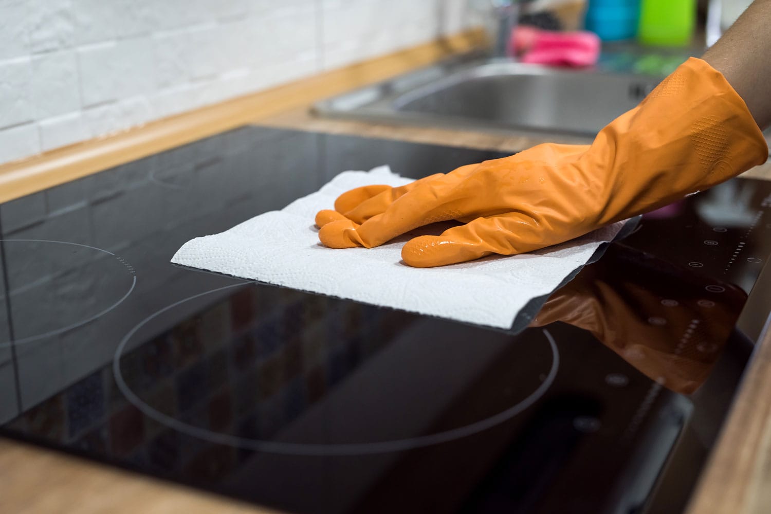 woman washing modern cooktop cooking panel in kitchen