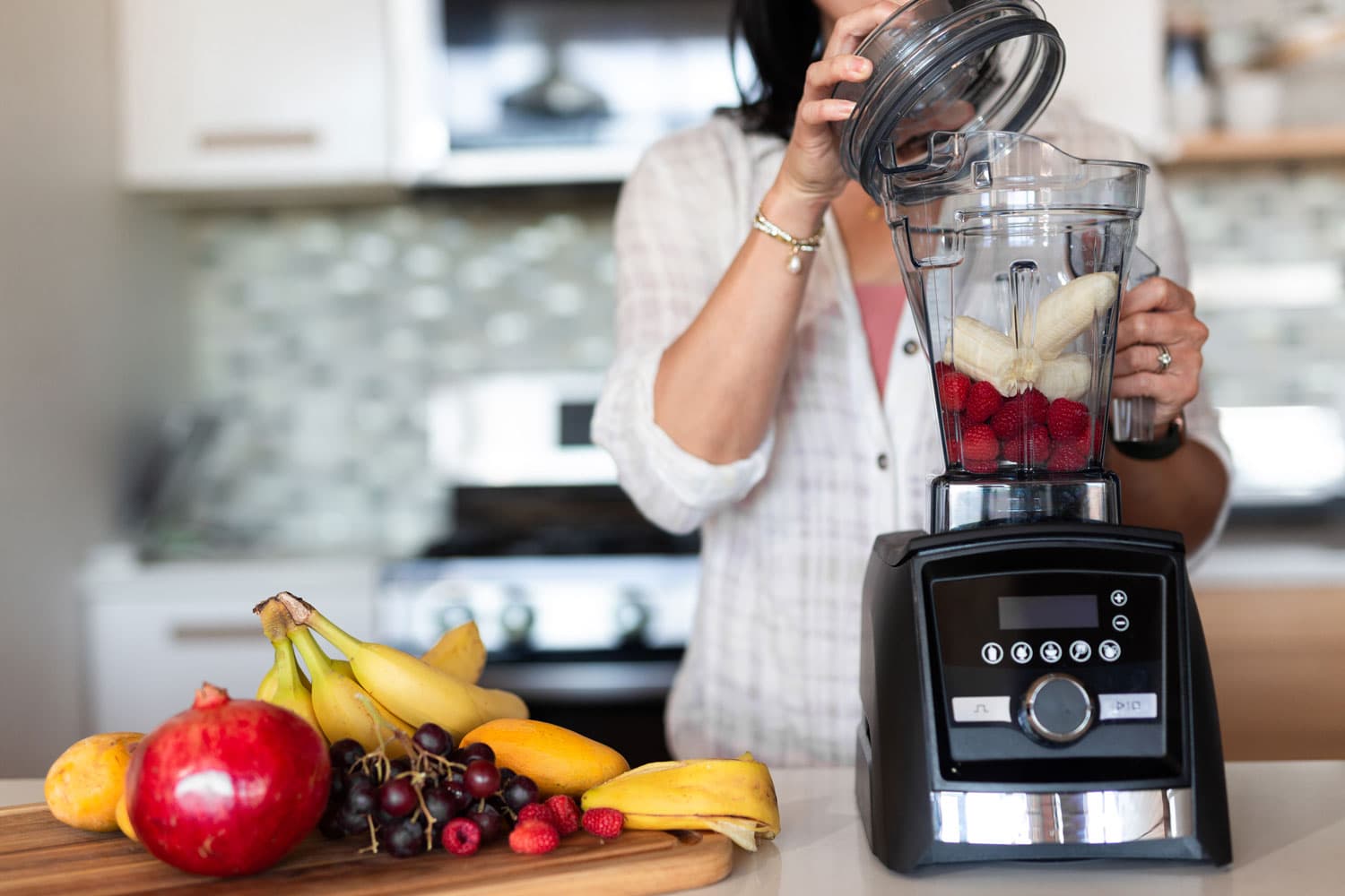 Woman making smoothie in the kitchen using Vitamix blender