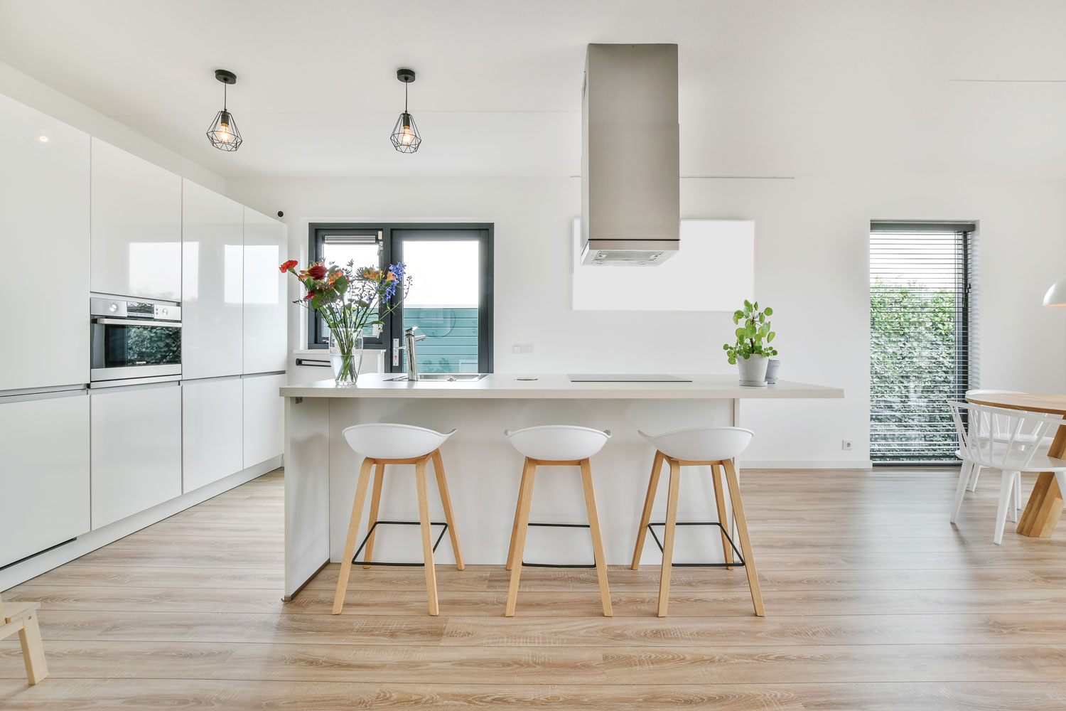 Light brown laminated kitchen flooring with white painted walls and matching white cabinets