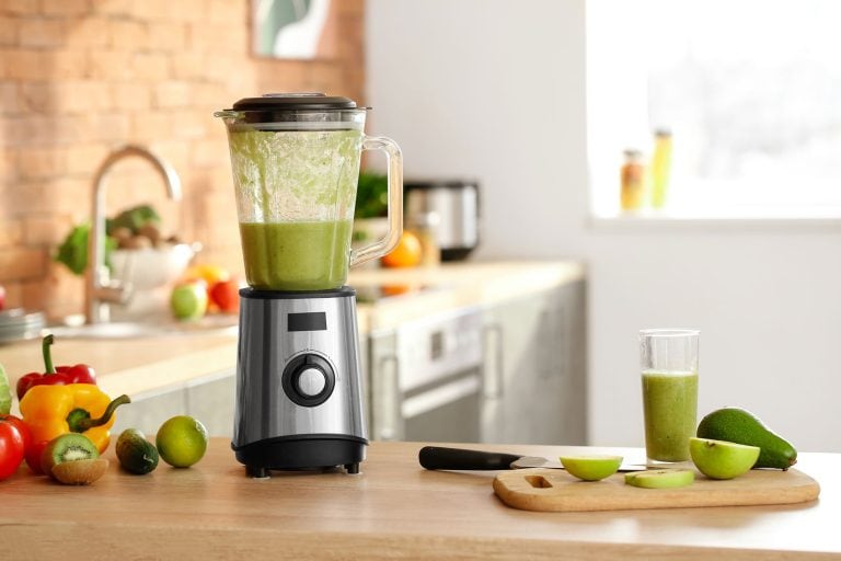A blender inside the kitchen filled with fruits and vegetables