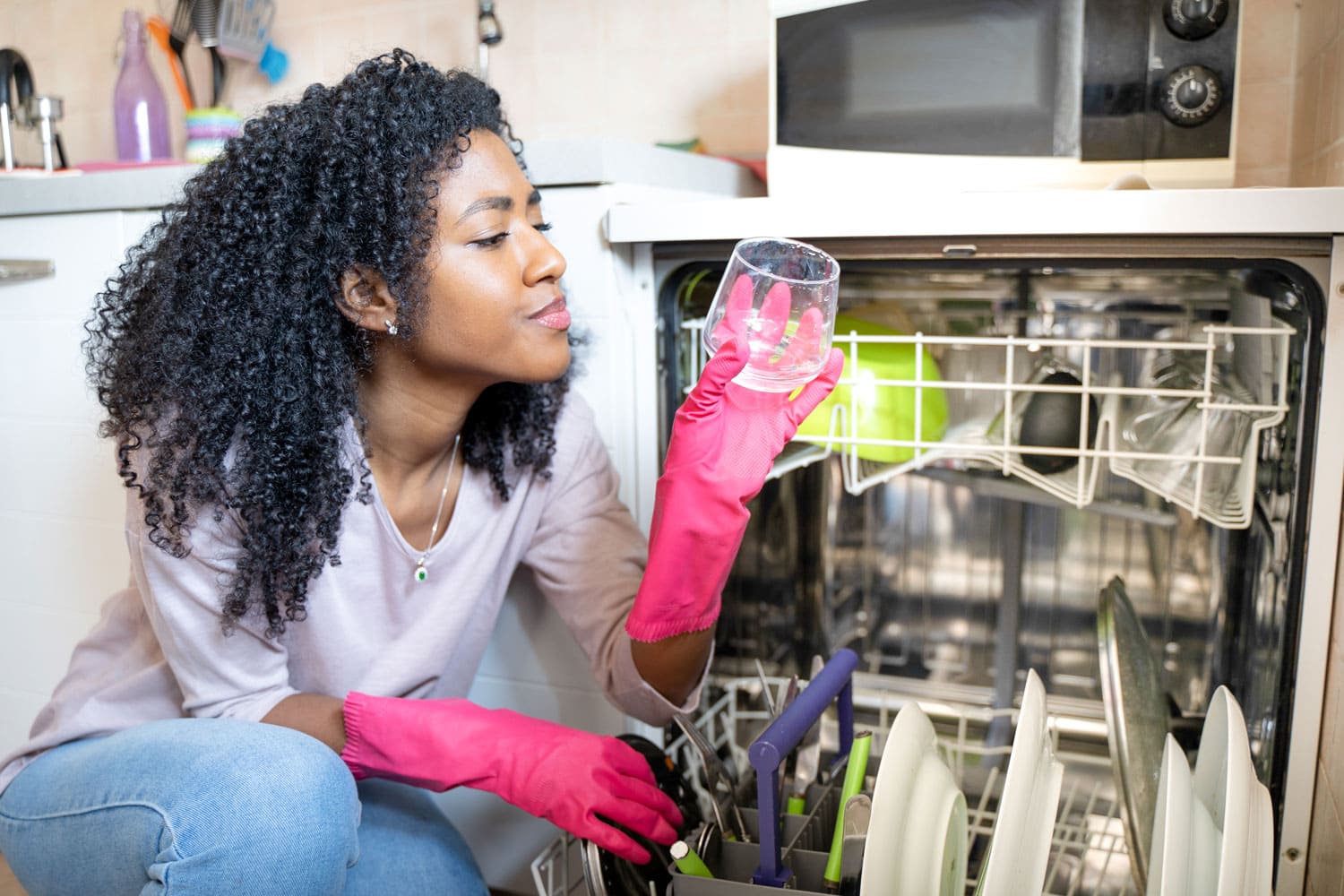 One black woman checking broken dishwasher at home