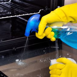 Man cleaning the oven using an oven cleaner, Can You Use Oven Cleaner On A Toaster Oven? Should You? - 1600x900