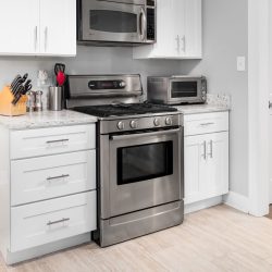 A GE microwave placed in a white kitchen, How To Remove A GE Oven Door [Step By Step Guide] - 1600x900