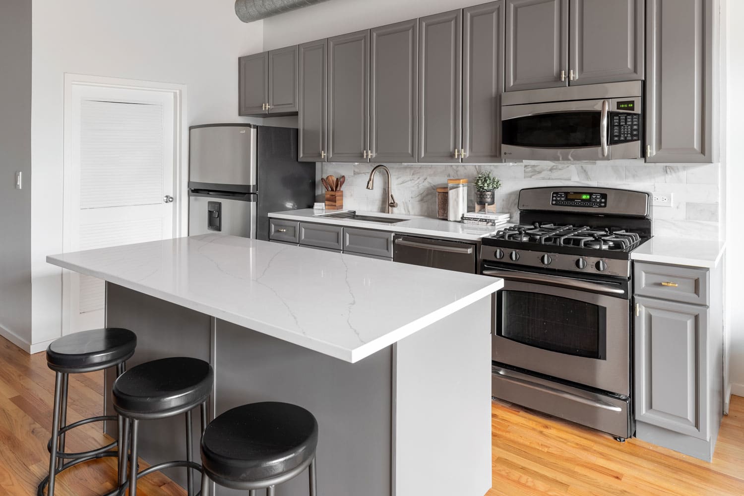 Interior of a white and gray themed kitchen with a GE oven and other GE appliances